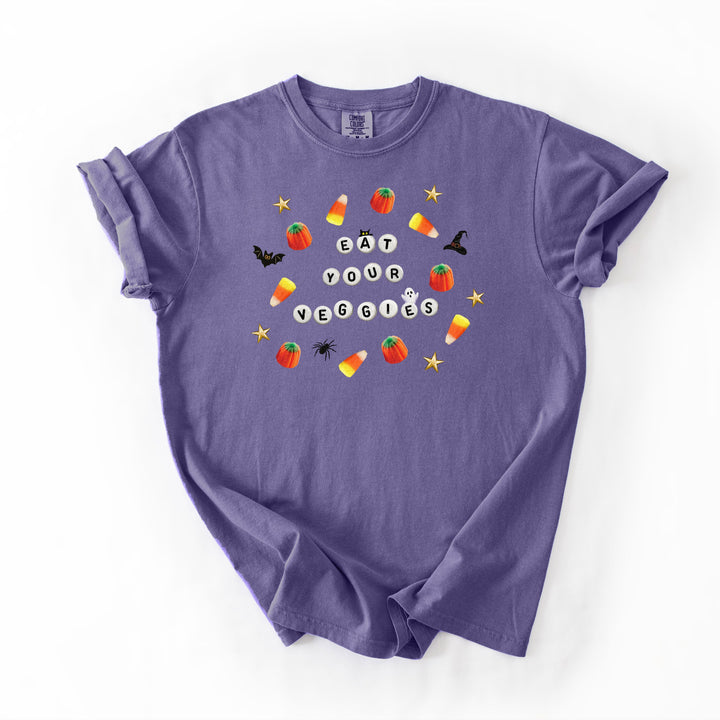 A purple short-sleeve t-shirt with a 'Eat Your Veggies' Halloween graphic, laid flat on a white background.