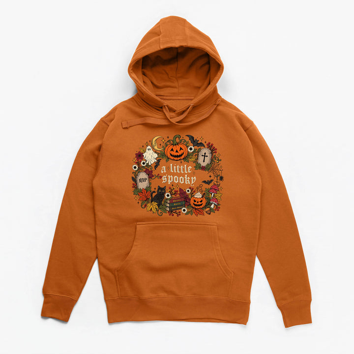 An orange pullover hoodie with a festive Halloween graphic on the chest that reads 'a little spooky' surrounded by pumpkins, ghosts, and autumn elements, displayed on a clean white background.